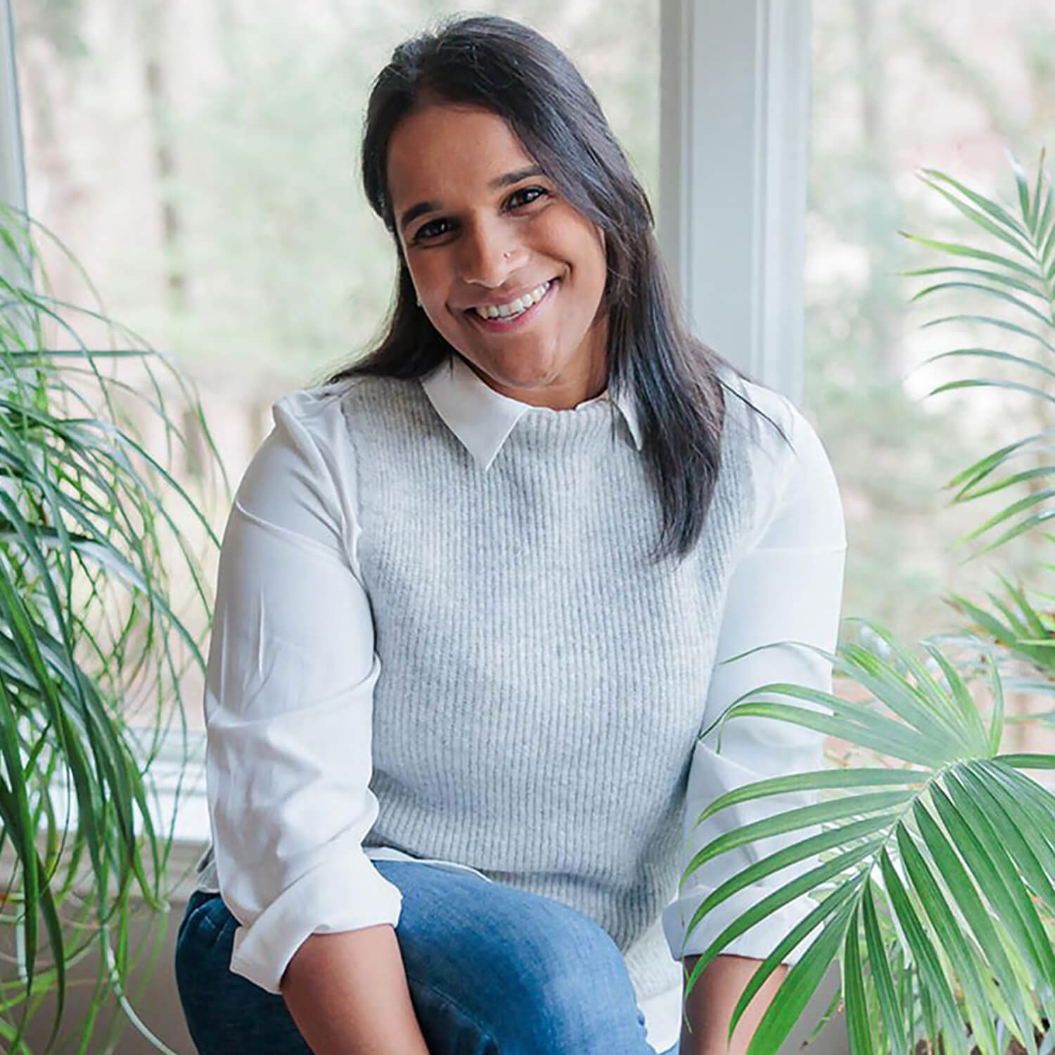 Stephanie, a therapist with an attachment-based and trauma-focused approach, smiles warmly while seated in a bright room with greenery. As a psychotherapist and certified yoga teacher, she values the mind-body connection in healing. Her compassionate demeanor reflects her dedication to helping clients understand their past, embrace the present, and envision a healthier future.